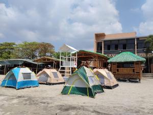 a group of tents in the sand in front of a building at Baywatch Beach Resort in Olongapo