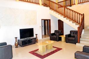 a living room with a tv and a staircase at Beach Sand Hotel & Resort, Cotonou in Cotonou