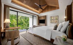 a bedroom with a large white bed and a window at Anantara Ubud Bali Resort in Payangan
