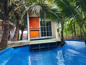 a swimming pool with palm trees in front of a house at Min Land Resort in Ban Lan Nok