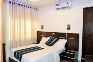 a bedroom with a bed with white sheets and black and white pillows at Beach Sand Hotel & Resort, Cotonou in Cotonou