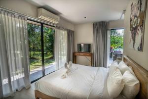 a bedroom with a bed with white sheets and large windows at CocoCool Villas in Hinkong +33 photos