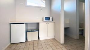 a kitchen with a counter with a microwave and a refrigerator at Higgins Lane Motel in Margaret River Town