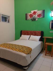 a bedroom with a bed with a green wall at Edotel Tebe Syariah in Rampal