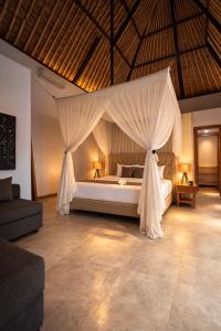 a bedroom with a large bed with mosquito net at Balidroomvilla's in Candidasa