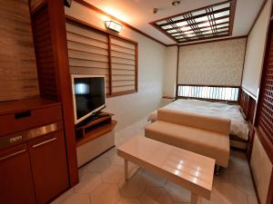 a small room with a bed and a television at ホテルラフィネ in Toyonaka