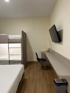 a bedroom with a bed and a desk with a tv at Serenity Homestay Penuin Batam in Batam Center