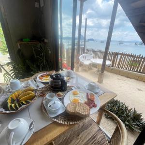 a breakfast table with food on it with a view of the ocean at Balili Villas Free Use Mtorbike During Stay in El Nido