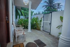 a porch with a rocking chair and a gate at Nasha Lanka House in Koggala