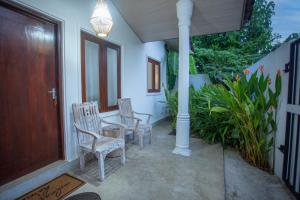 a porch with two chairs and a table and a door at Nasha Lanka House in Koggala