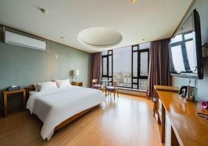 a bedroom with a white bed and a large window at Nabeeya Hotel in Siheung