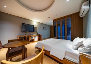 a bedroom with a bed and a table and a tv at Nabeeya Hotel in Siheung