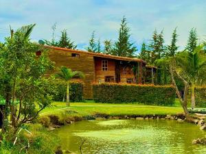 a wooden house with a pond in front of it at Cabañas ecológicas Xuetama in Villa de Leyva +25 photos