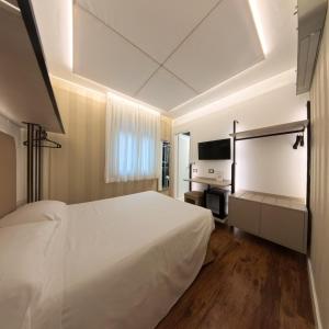 a bedroom with a large white bed and a television at Hotel Aurora in Tivoli Terme