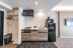 a kitchen with a black refrigerator and a sink at Apartment Hotel 11 Shinsekai in Osaka