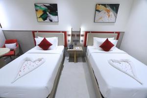 two beds with red pillows in a room at Antra Luxe in Anumalkudūru