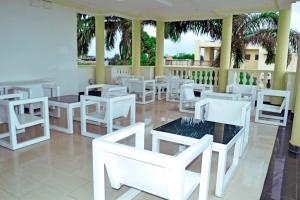 a restaurant with white tables and white chairs at Beach Sand Hotel & Resort, Cotonou in Cotonou