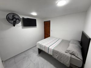 a bedroom with a bed and a fan on a wall at Posada Del Puerto in Armenia