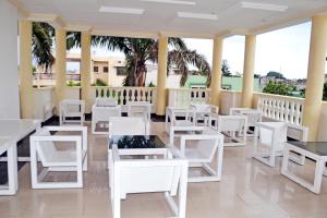 a restaurant with white tables and white chairs at Beach Sand Hotel & Resort, Cotonou in Cotonou