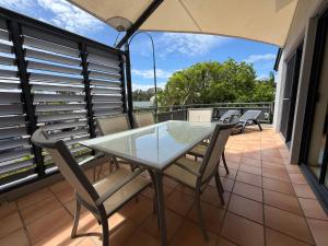 a balcony with a glass table and chairs at Byron Quarter Apartments in Byron Bay +36 photos