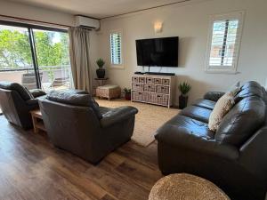 a living room with leather furniture and a flat screen tv at Byron Quarter Apartments in Byron Bay