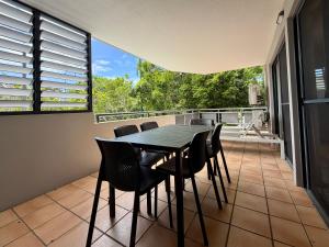 a dining room with a table and chairs on a balcony at Byron Quarter Apartments in Byron Bay