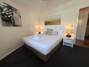a bedroom with a large white bed with two lamps at Byron Quarter Apartments in Byron Bay