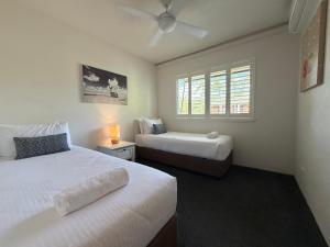 a bedroom with two beds and a window at Byron Quarter Apartments in Byron Bay