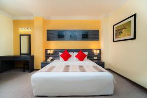 a bedroom with a large white bed with red pillows at HIG Hotel & Convention in Kuah