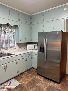 a kitchen with a stainless steel refrigerator and white cabinets at The Cleveland Cottage in Brookhaven