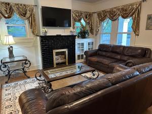 a living room with a leather couch and a fireplace at The Cleveland Cottage in Brookhaven