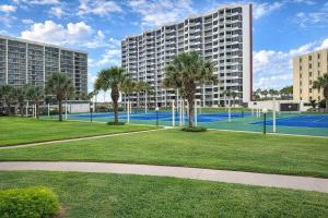 a tennis court with palm trees and a large building at Resort like super heated pool & direct beach front in South Padre Island