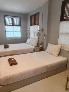 two beds in a room with two windows at บ้านสุขใจ อัมพวา in Samut Songkhram
