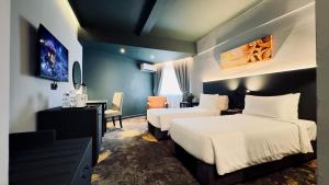 a hotel room with two beds and a desk and chair at Trigo Hotel Kuala Lumpur in Kuala Lumpur