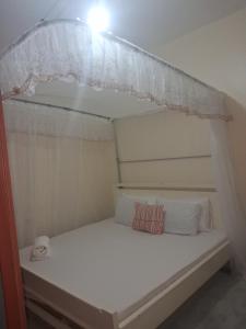 a small white bed with a canopy in a room at PAZURI - Homes in Voi