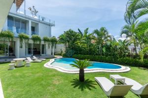 a garden with a swimming pool and chairs and a house at Luxury 5BR Villa with Rooftop BBQ Pool 500M to Beach in Canggu