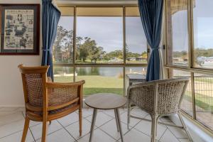 a room with chairs and a table and windows at Holiday on the Water in Sussex Inlet