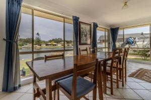 a dining room with a table and chairs and large windows at Holiday on the Water in Sussex Inlet