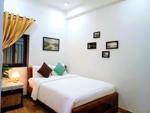 a bedroom with a bed with white sheets and a window at PHỐ XANH hotel - STAY 24H in Hoi An