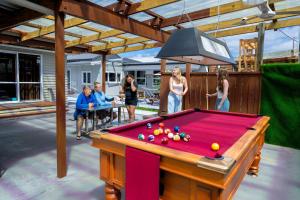 a group of people standing around a pool table at FlyingPig Backpacker Rotorua in Rotorua