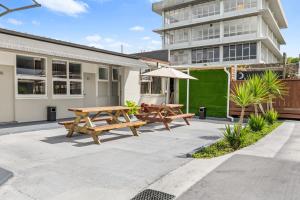 two picnic tables and an umbrella in front of a building at FlyingPig Backpacker Rotorua in Rotorua