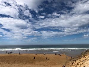 a group of people on a beach near the ocean at Anza surf spot in Agadir