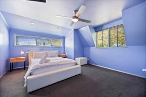 a blue bedroom with a bed and a ceiling fan at La Maison Bleue in Ballarat