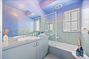 a bathroom with a sink and a tub and a mirror at La Maison Bleue in Ballarat