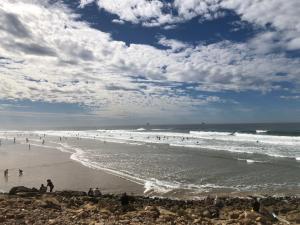 a group of people on a beach with the ocean at Anza surf spot in Agadir