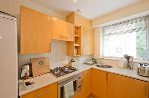 a kitchen with wooden cabinets and a stove top oven at St Christopher's Place Serviced Apartments by Globe Apartments in London