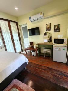 a bedroom with a bed and a desk with a microwave at บ้านสุขใจ อัมพวา in Samut Songkhram