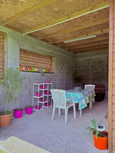 a patio with a table and chairs and a wooden ceiling at Éco-Domaine du volcan, Le Dahlia, studio 2 personnes in La Plaine des Cafres