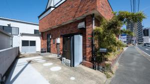 a brick building with a door on a street at LAZULI Fukutsu in Fukuoka