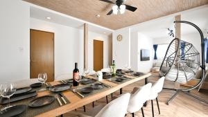 a dining room with a wooden table and white chairs at LAZULI Fukutsu in Fukuoka